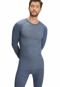 Maglia termica a maniche lunghe e leggings attillati in un tessuto blu scuro con texture, dotati di scollatura rotonda e logo del brand discreto.