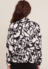 Schwarze und weiße Bomberjacke mit floralem Muster, aus strukturiertem Stoff, mit gestepptem Design und gerippten Bündchen, mit einem Reißverschluss auf der Rückseite.