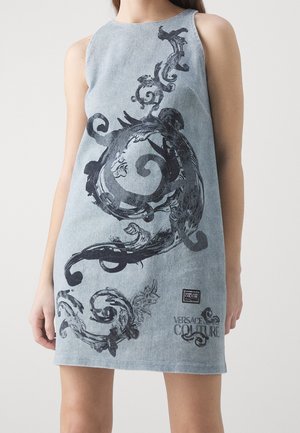 Robe sans manches en denim bleu clair avec un imprimé baroque orné sombre et tourbillonnant ainsi qu'une étiquette "Versace Jeans Couture" sur le bas devant.