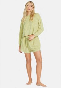 Limegrönt loungeset med texturerad tyg, bestående av en kortärmad sweatshirt och shorts med dragsnöre, båda bekväma och avslappnade i design.