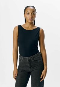 Schwarzer ärmelloser Body mit runder Ausschnittform, kombiniert mit hochgeschnittenen dunkelgrauen Jeans. Glatte Textur, figurbetontes Design.