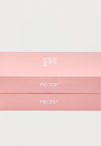 Ροζ χαρτόνι με γυαλιστερό φινίρισμα, με ετικέτα "PIECES® ADVENT CALENDAR" σε λευκό κείμενο, στοιβαγμένο πάνω σε ένα άλλο κουτί.