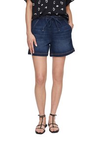 Szorty dżinsowe z elastycznym pasem, zapięciem na sznurek oraz bocznymi kieszeniami. Ciemnoniebieski kolor z podwiniętym dołem i kontrastującymi szwami.