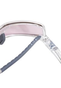 Occhiali da sole trasparenti con lenti rosa, gamba flessibile grigia e superficie interna testurizzata. Marchi CE e UK sul braccio. Design leggero e sportivo.