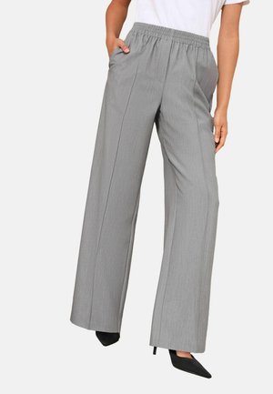 Graue Hose mit weitem Bein aus strukturiertem Stoff, elastischem Bund und Seitentaschen, kombiniert mit schwarzen, spitz zulaufenden Absätzen.