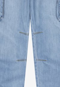 Jean en denim bleu clair avec des fentes horizontales cousues au-dessus et en dessous des genoux sur les deux jambes.
