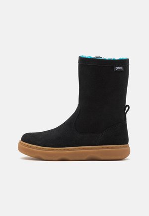 Czarny zamszowy botek za kostkę z miękką, miękką podszewką w kolorze niebieskozielonym, gumową podeszwą oraz pętelką z tyłu ułatwiającą zakładanie. Charakteryzuje się minimalistycznym przeszyciem.