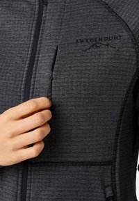 Mörkgrå zip-up jacka med texturerad tyg som har en logotyp, sidoficka och kontrasterande svart dragkedja; inkluderar justerbar dragsko.