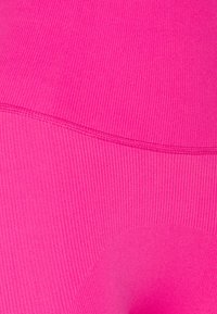 Tessuto elasticizzato fucsia con texture a costine. Le cuciture creano contorni sottili. Finitura liscia con vita elasticizzata.