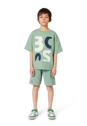Mint green cotton short-sleeve t-shirt with large white and navy graphic letters, paired with matching shorts and green and white sneakers.