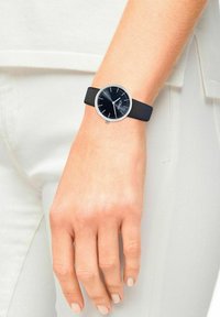 Schwarze Silikonarmbanduhr mit rundem Ziffernblatt, silbernen Akzenten und Stundenmarkierungen. Am Handgelenk getragen, zeigt ein schlichtes und modernes Design.