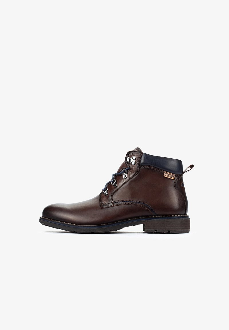 Bottes chelsea en cuir marron avec une finition lisse, lacets bleus, œillets en métal et semelle en caoutchouc. Présente un logo d'accent marron sur le côté.