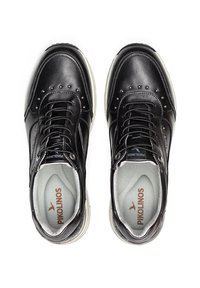 Zapatillas negras de cuero con punta redonda, diseño de cordones, tachuelas decorativas plateadas y un forro interior gris. Logo de la marca visible en la plantilla.