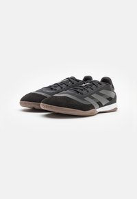 Zapatillas deportivas negras con una parte superior de ante texturizado y malla transpirable. Cuenta con rayas grises, un perfil bajo y una suela de goma.
