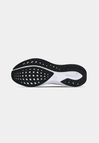 Semelle de chaussure de course noir et blanc avec motif en gaufre et logo de la virgule Nike sur un fond blanc uni.