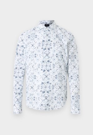 Chemise blanche à manches longues avec un motif symétrique bleu marine de fleurs et de volutes, col classique et coupe ajustée.