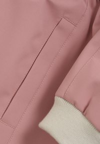 Svetloružová bunda s hladkým, matným materiálom, s krémovými rebrovými manžetami a nenápadným detailom bočnej vrecka.