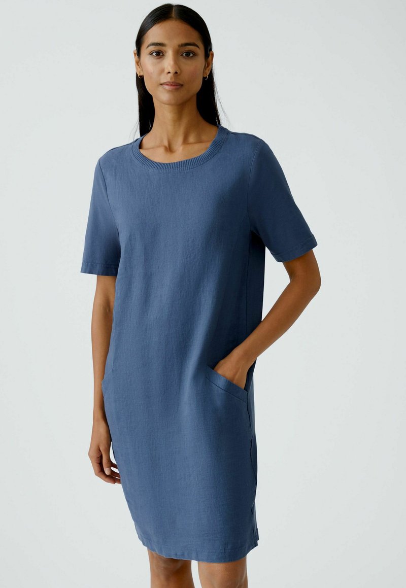 Blaues, knielanges Kleid mit kurzen Ärmeln, Rundhalsausschnitt und seitlichen Taschen. Weicher, strukturierter Stoff mit einem lässigen, entspannten Schnitt.