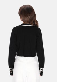 Fekete cropped pulóver texturált mintával, gyöngy részletekkel a galléron és a mandzsettákon, hosszú ujjakkal és elegáns kivitelben.