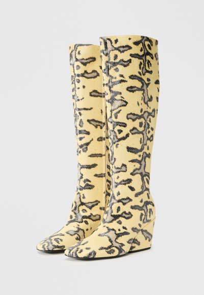 Μπότες μέχρι το γόνατο με σχέδιο κίτρινης ερπετοειδούς υφής, με μυτερή μύτη και πλατφόρμα-τακουνάκι με υφή σε μαύρο χρώμα.