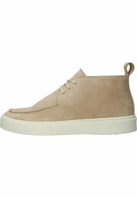 Botas de tobillo de ante beige con punta redonda, suela blanca plana y un cordón minimalista. Presenta un tirador en la parte trasera para un fácil calzado.