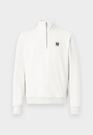 Pull-over blanc à demi-fermeture éclair avec poignets et ourlet côtelés, arborant un petit patch logo carré noir et blanc sur le côté gauche de la poitrine.