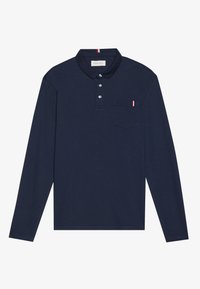 Marineblå langermet polo skjorte laget av bomull, med en placket med tre knapper, en brystlomme med en rød, hvit og blå aksentstripe.