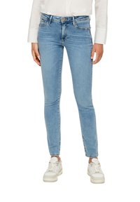 Lichtblauwe skinny jeans van denim, met een klassiek vijfzakkenontwerp en zilveren hardware. G gedragen met witte sneakers.