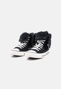 Zapatillas altas de ante negro con un cuello plegable forrado de pelo, suela de goma blanca y diseño clásico de cordones con ojales de metal.