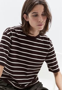 Brun og hvid stribet kortærmet t-shirt lavet af blødt stof, med rund halsudskæring og afslappet pasform.