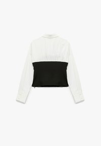 Zwart-witte cropped shirt met een gestructureerd ontwerp, lange mouwen en een knoopsluiting. De stof heeft een gladde textuur.