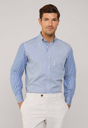 Camicia azzurro chiaro con righe verticali bianche, maniche lunghe, taschino sul petto e dettagli blu a contrasto sui polsini.