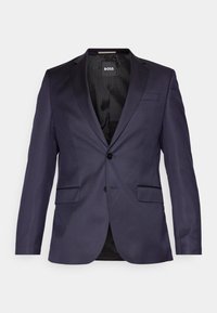 Marineblauwe op maat gemaakte blazer met een enkele knoop, twee voorzakken en een gladde textuur. De binnenzijde heeft een gemusterde zwarte voering en branding.