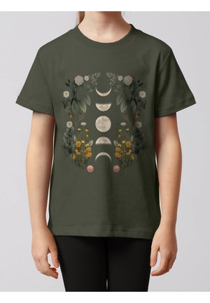 Enfant portant un t-shirt vert olive avec un motif floral encadrant les phases de la lune en tons blanc, jaune et vert.