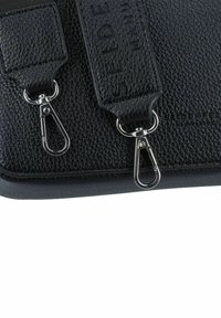 Borsa in pelle nera texturizzata con hardware argentato, cinture rimovibili e dettaglio del marchio impresso sulla tracolla.