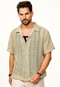 Helles beige Kurzarmhemd aus offen gestricktem Material mit Knopfvorderseite, kragen und strukturiertem Design.