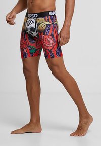 Színes, grafikai dizájnnal rendelkező boxer alsóneműk, amelyeken koponyák és rózsák láthatók. Rugalmas anyagból készült, fekete rugalmas derékpánttal a logóval, térd fölé érő hosszúságú.