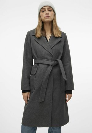 Manteau en mélange de laine gris avec une taille ceinturée, des revers en pointe et des poches plaquées. Il présente des manches longues et une coupe droite, associé à un bonnet en tricot.