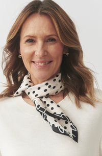 Foulard di seta in crema con pois neri e un motivo contrastante nero. Presenta una morbida texture e si drappeggia elegantemente attorno al collo.