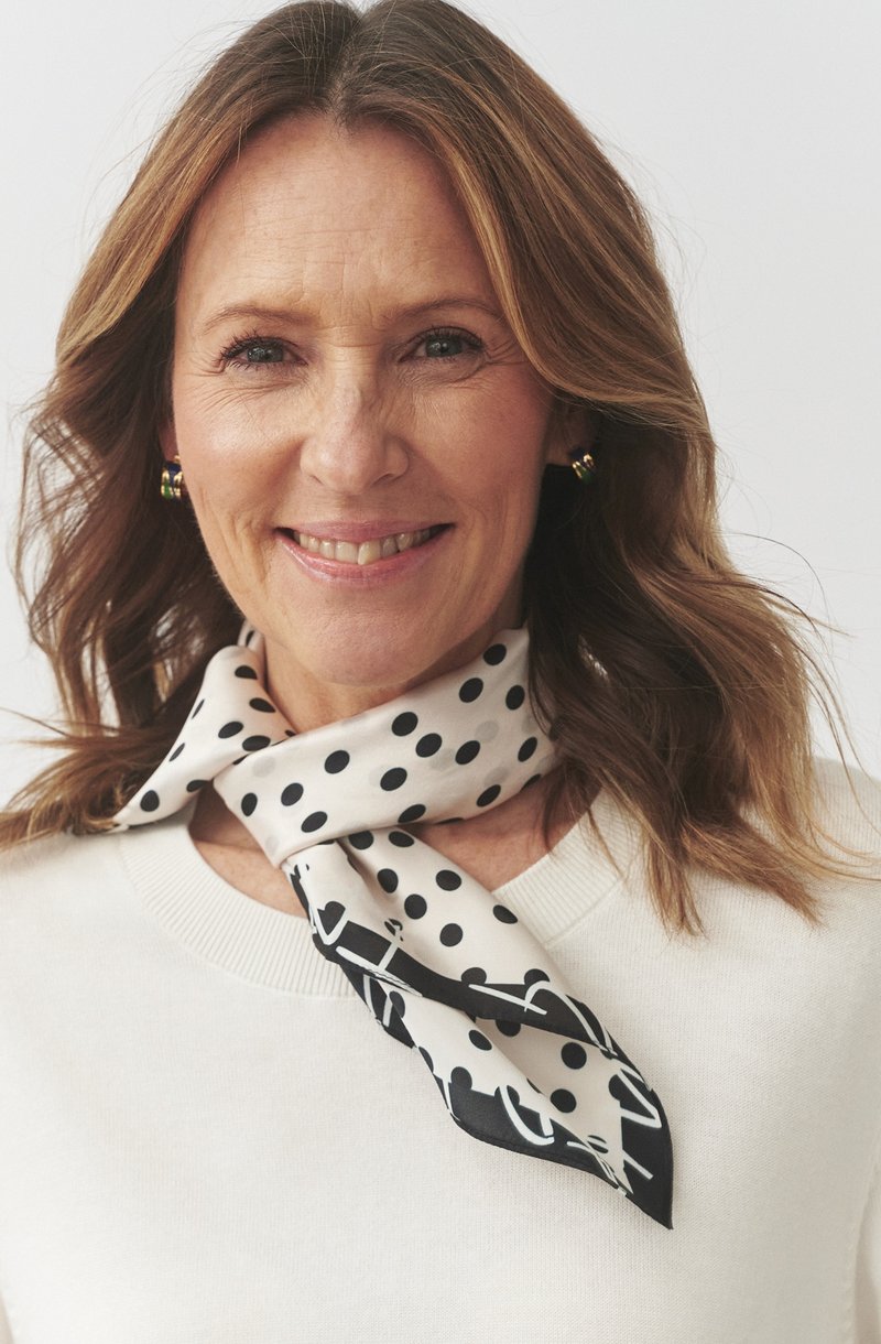 Foulard di seta in crema con pois neri e un motivo contrastante nero. Presenta una morbida texture e si drappeggia elegantemente attorno al collo.