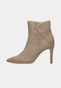 Botín de tobillo de punta afilada en ante beige con un diseño elegante y un tacón alto y delgado. Presenta una textura suave y detalles de costura sutiles.