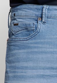 Lichtblauwe denim jeans met een vervaagde wassing, met een klassiek vijfzakendesign, subtiele stikseldetails en een merketiket op de achterzak.