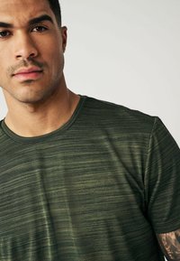 Grønne tekstureret t-shirt med runde halsudskæring og korte ærmer, med et subtilt vandret stribemønster og et blødt, let stof.