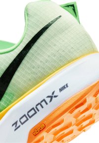 Talons de chaussures de course Nike ZoomX vertes et blanches avec un swoosh noir et des détails de grip de semelle extérieure Vibram orange.
