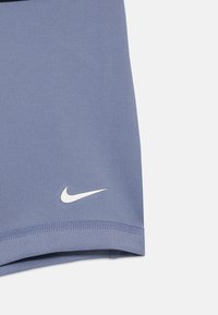 Nike sportiniai šortai šviesiai violetinės spalvos, pagaminti iš lygaus audinio. Yra baltas Nike swoosh logotipas ir tvarkingas apvadas.