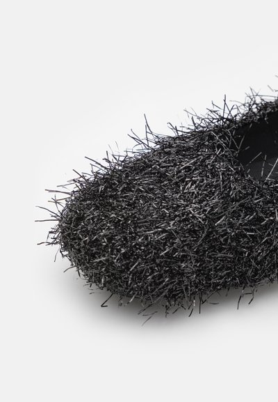 Black flat shoe made of textured, hairy material with twisted fibers, rounded toe, and a smooth interior surface.
