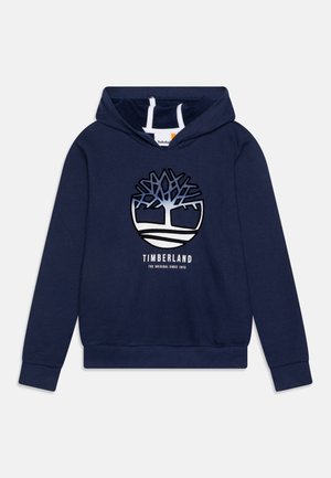 Sweat à capuche bleu marine en coton avec une poche kangourou à l'avant, arborant un logo d'arbre et le texte "Timberland" en blanc sous le logo.