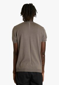 Maglione a maniche corte, aderente, in tessuto di maglia marrone chiaro, con cucitura centrale posteriore e dettagli a costine su collo e orlo.