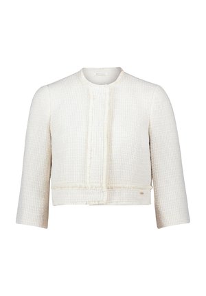 Veste blanche courte en tissu texturé avec des bords légèrement effilochés, un col rond et des manches trois-quarts.