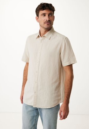 Helles beige Kurzarmhemd aus atmungsaktivem Stoff mit Knopfleiste und klassischem Kragen, kombiniert mit hellblauen Jeans.